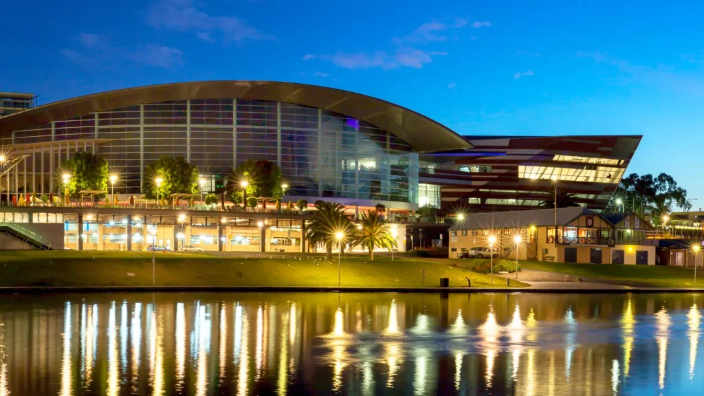 Adelaide Convention Centre at dusk with lights reflecting in Karrawirra Parri/River Torrens