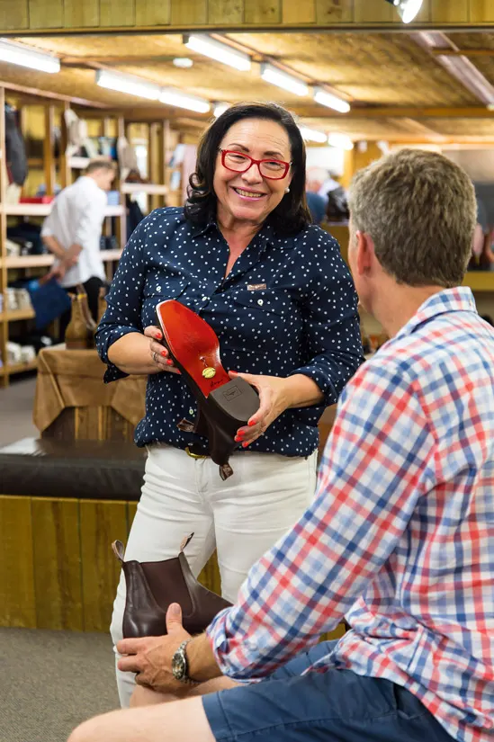 R.M.Williams employee presenting a client with a pair of boots